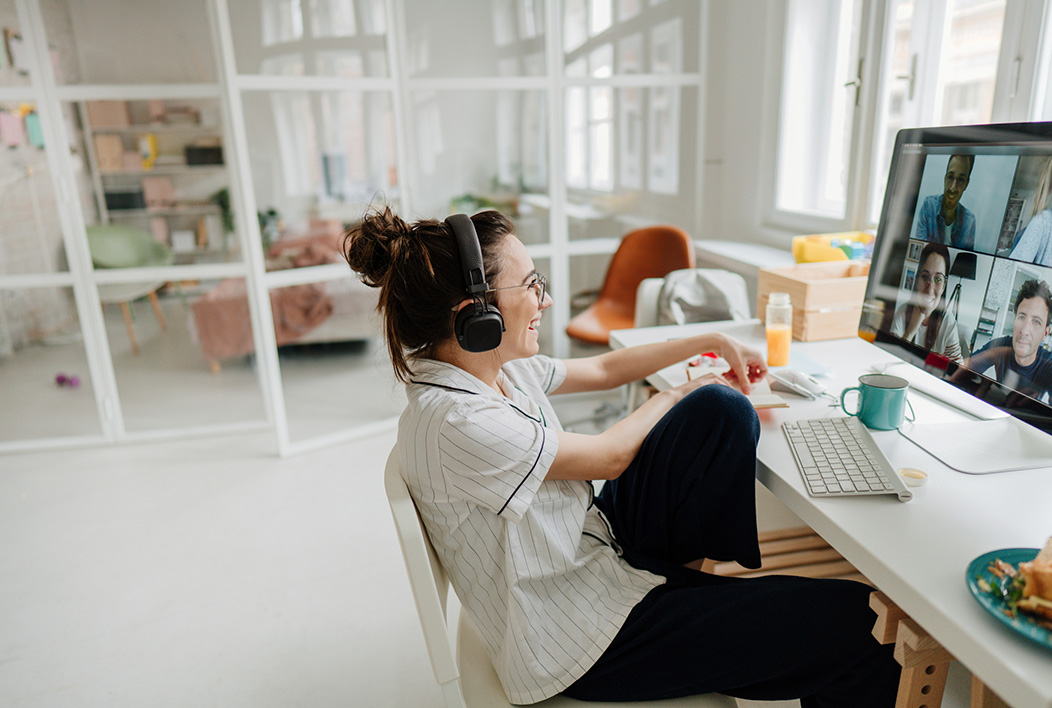 Smiling female college student wearing headphones participating in a video call with four people.