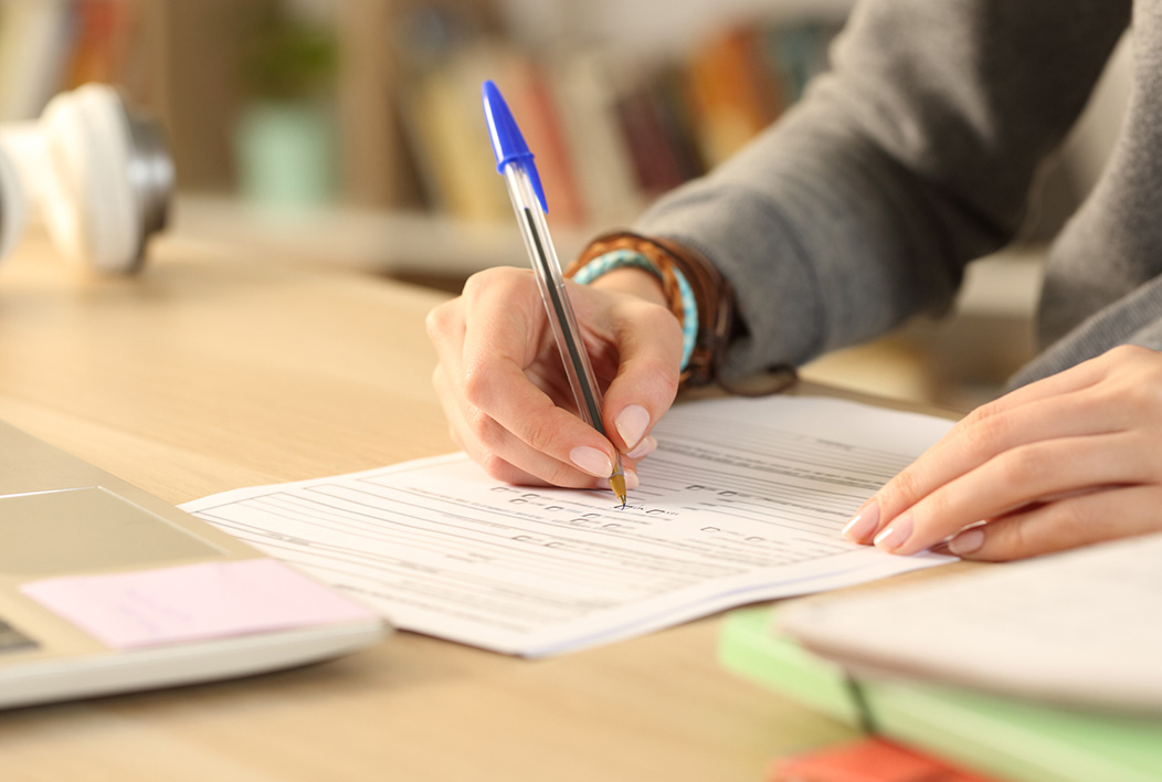 Female hands holding pen filling out paper test.