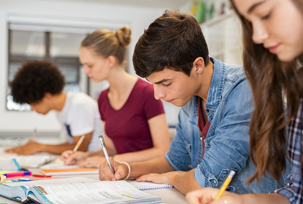 Four students sitting at a table taking a test.