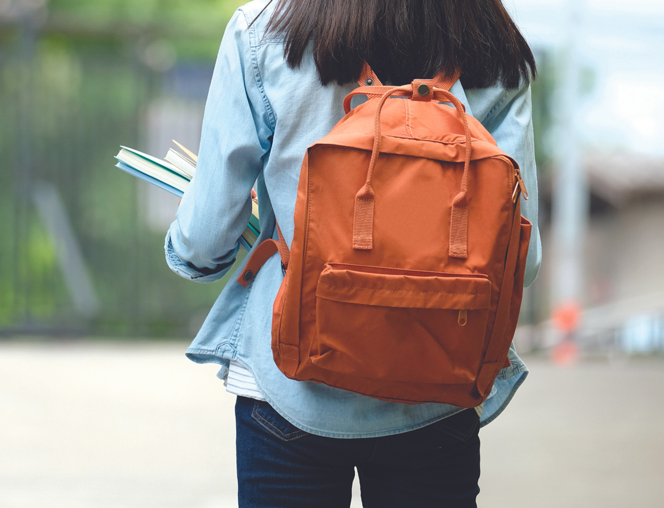 Female college student with long dark hair wearing a backpack planning her college journey.